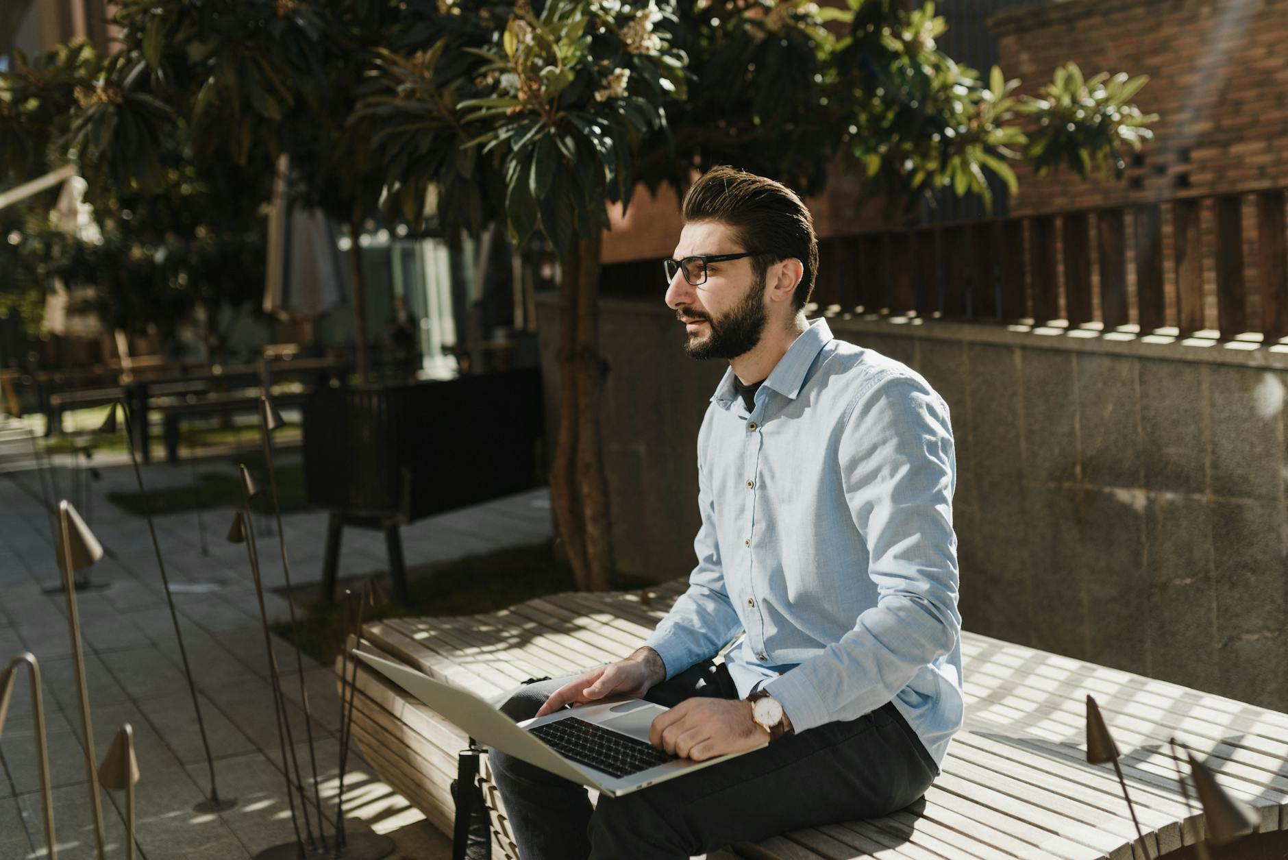 Mężczyzna w smart casual pracuje na laptopie na słonecznym tarasie